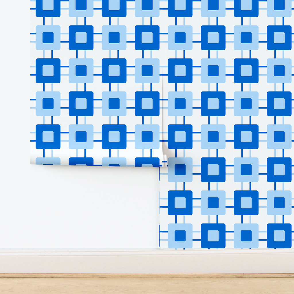 The artwork features a repeating geometric pattern of symmetrical shapes resembling elongated, curved diamonds or petals in various shades of blue and green. Each shape is split vertically with one half filled with a light blue and the other half filled with green or darker blue. The background is a light, almost pastel blue, which provides a soft yet vibrant backdrop. One of the blue shapes near the upper left contains a white starburst element, adding a focal point of brightness to the composition. The overall design conveys a modern, mid-century aesthetic with clean lines and harmonious color contrasts.